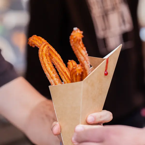 A cone of churros served during a churros bar event at a company